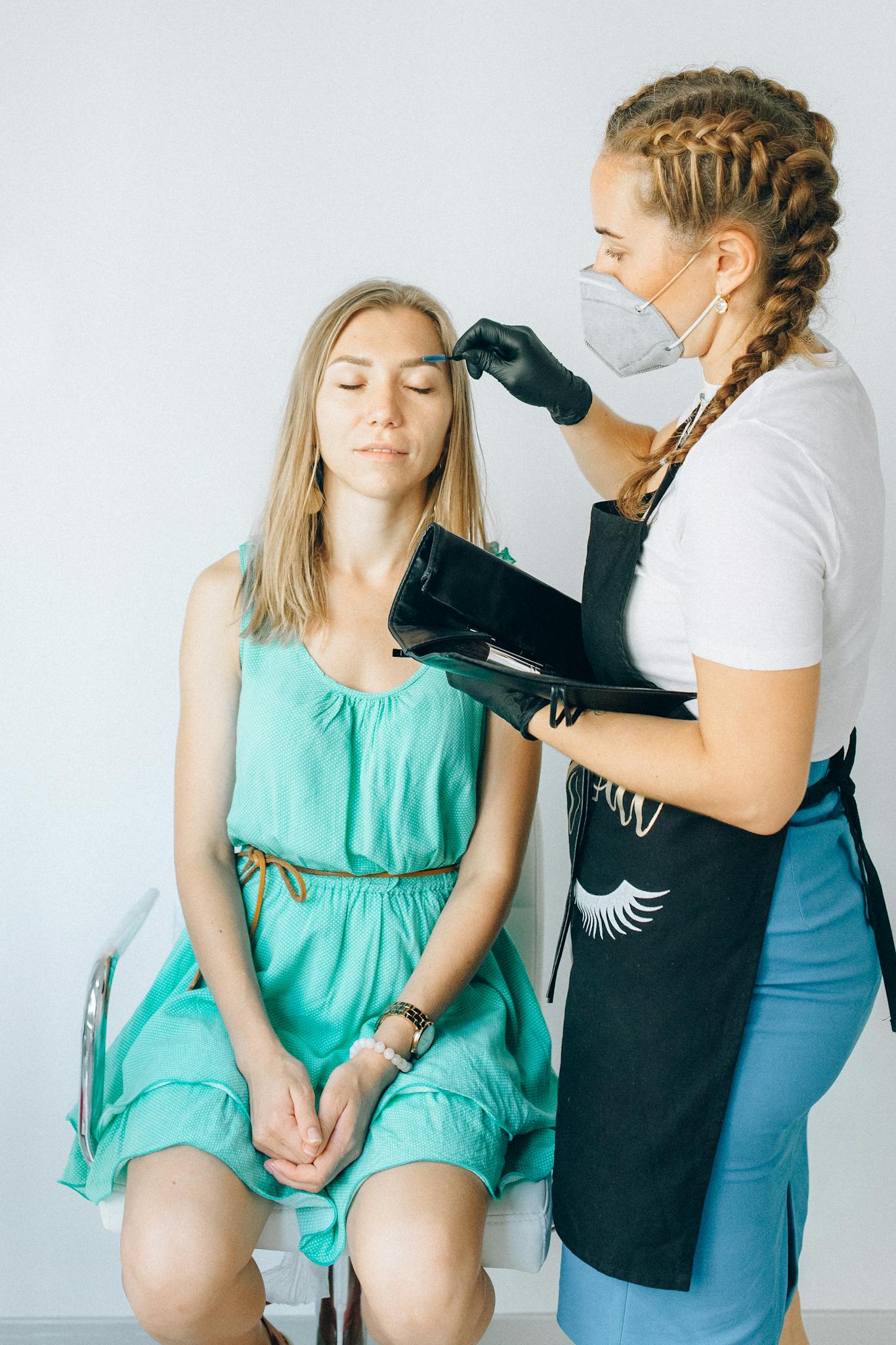 A beauty professional applying eyebrow treatment in a salon setting.
